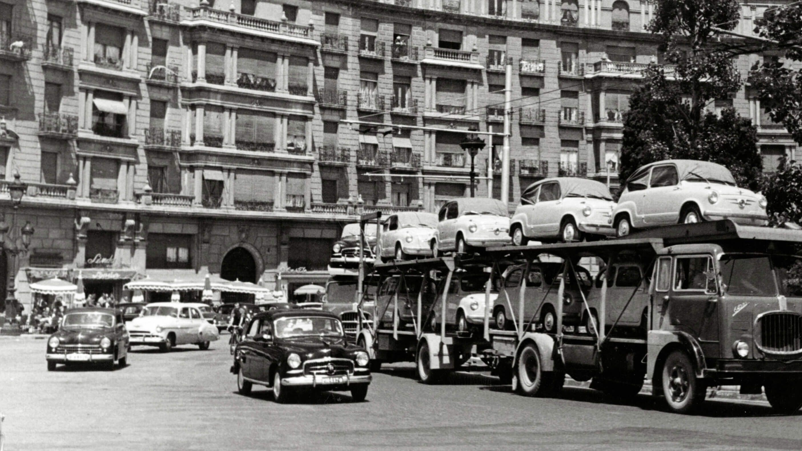 Schwarz weiß Aufnahme von 1950 mit einem LKW der mit den ersten SEAT Modellen beladen ist.